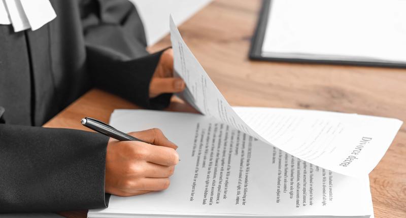 Female judge signing documents at workplace in courtroom