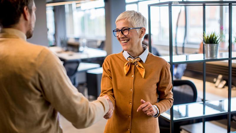Young business man and senior business woman shaking hands in the office