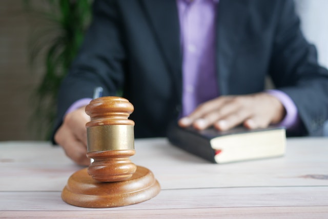 judge banging gavel with hand on book