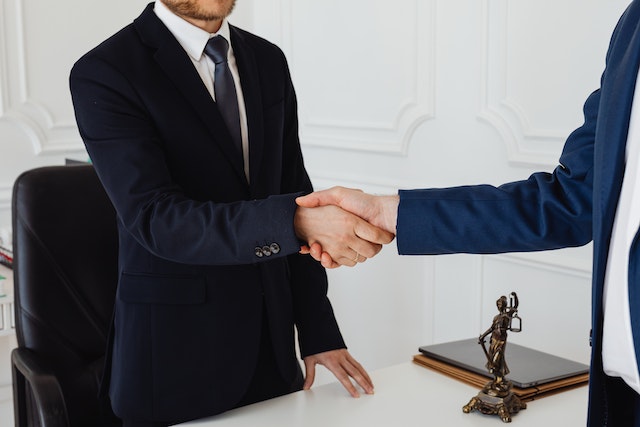 person shaking hands with lawyer in office