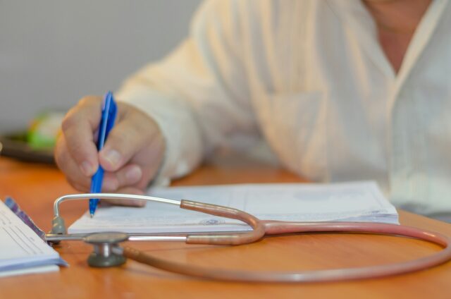 doctor writing on paper with stethoscope